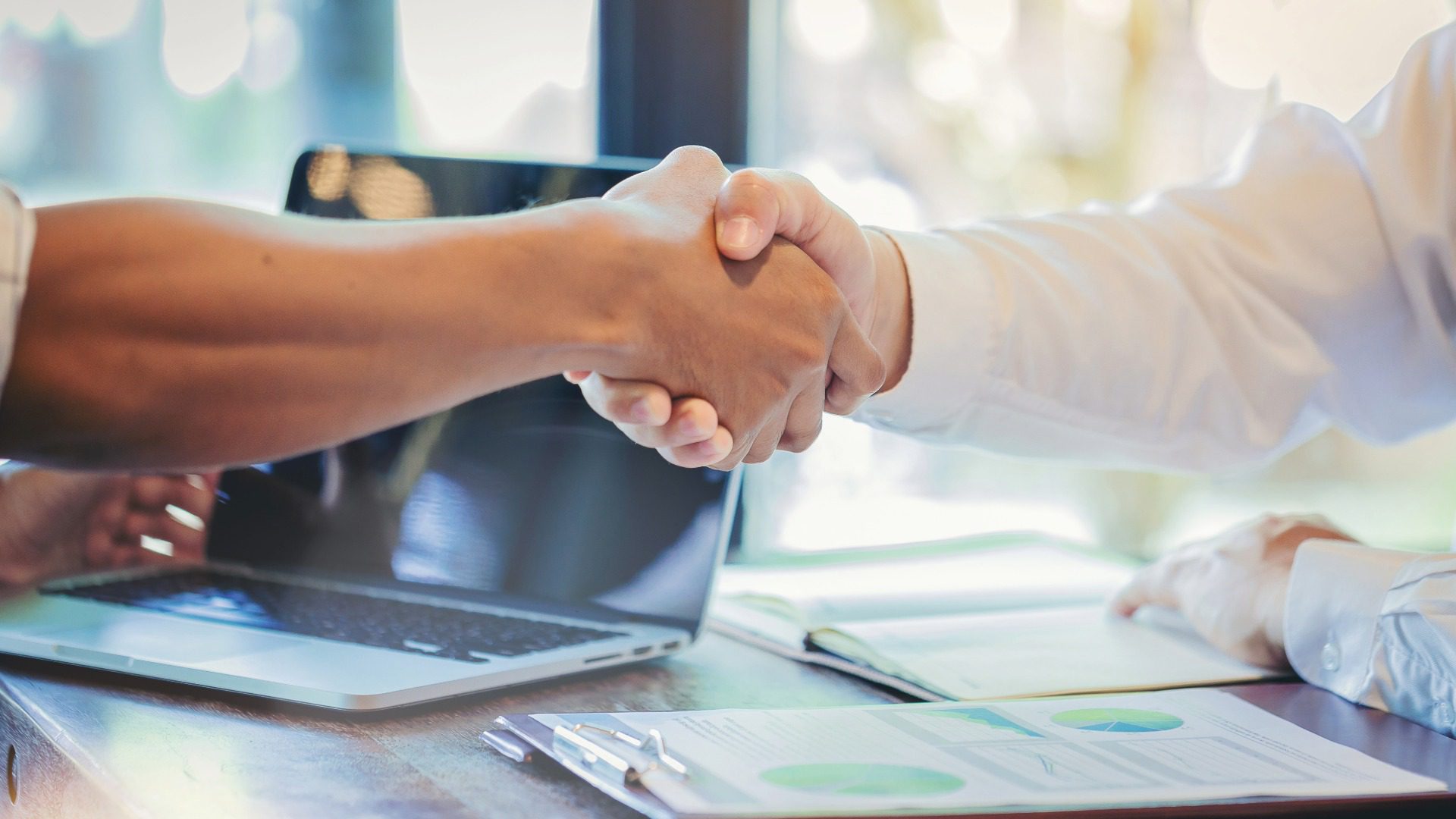 Business buyers and sellers reviewing financial projections and earn-out terms during a business sale negotiation