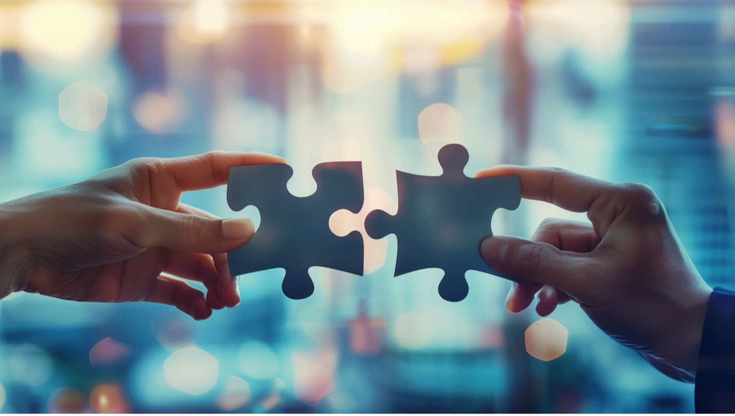 Two puzzle pieces connecting to symbolize business culture integration after a merger